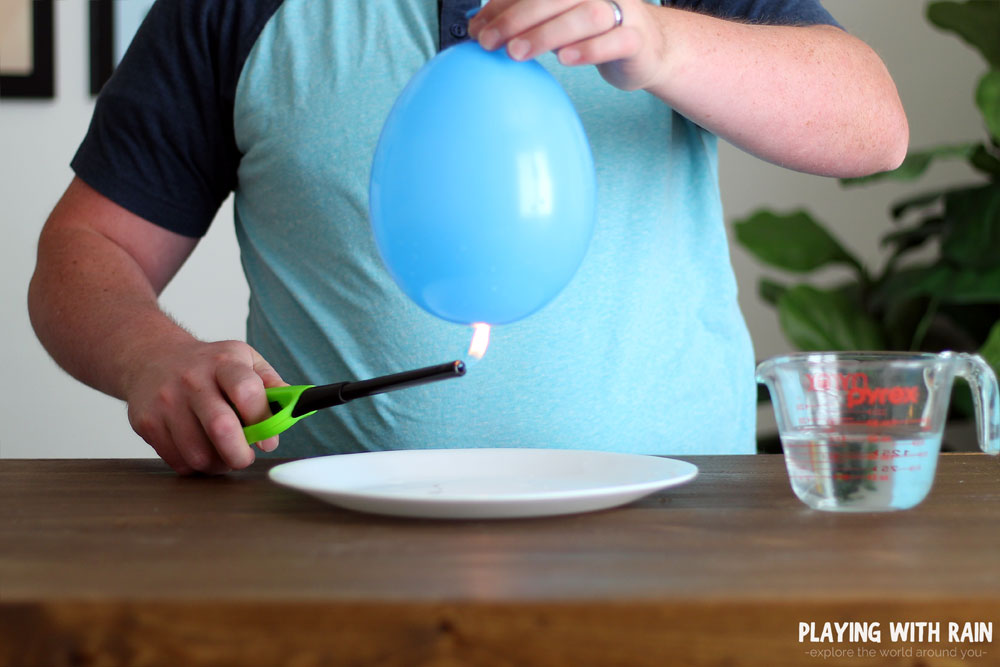 Lower the water filled balloon onto the flame.