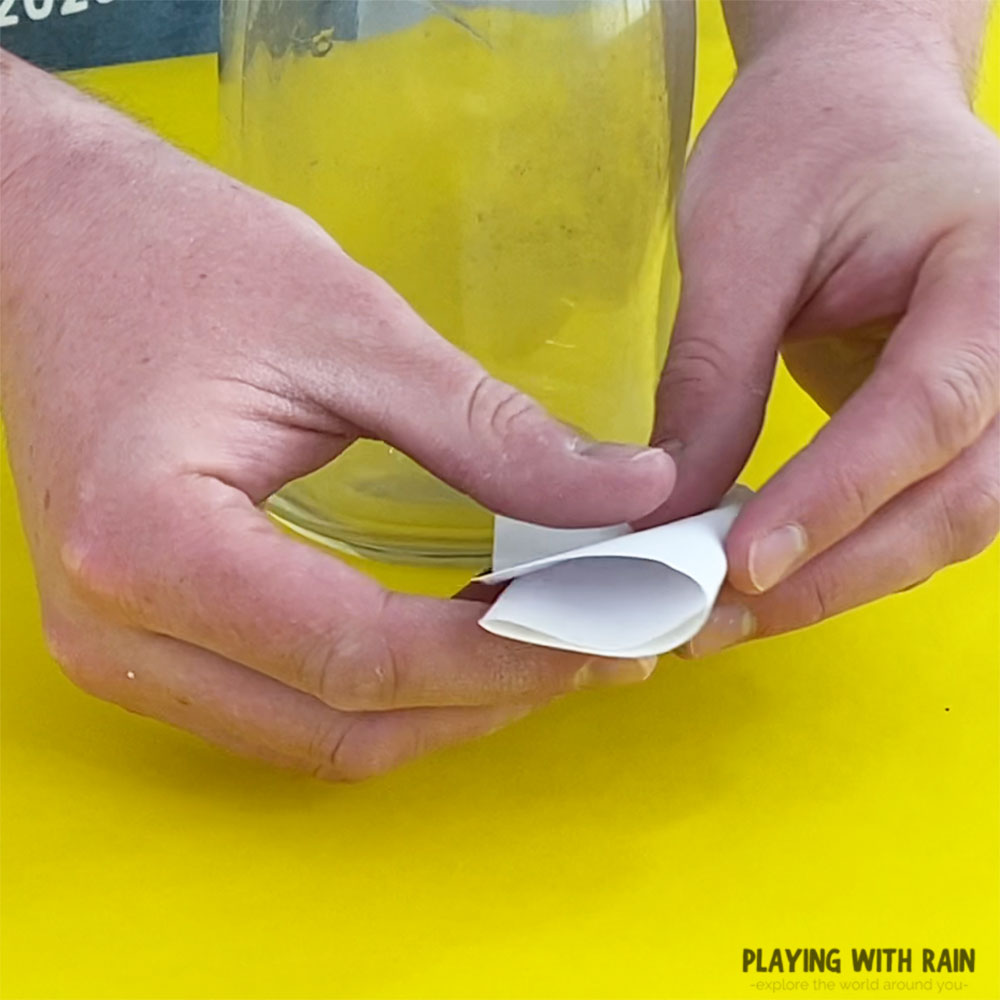 Fold some paper small enough to fit into the bottle