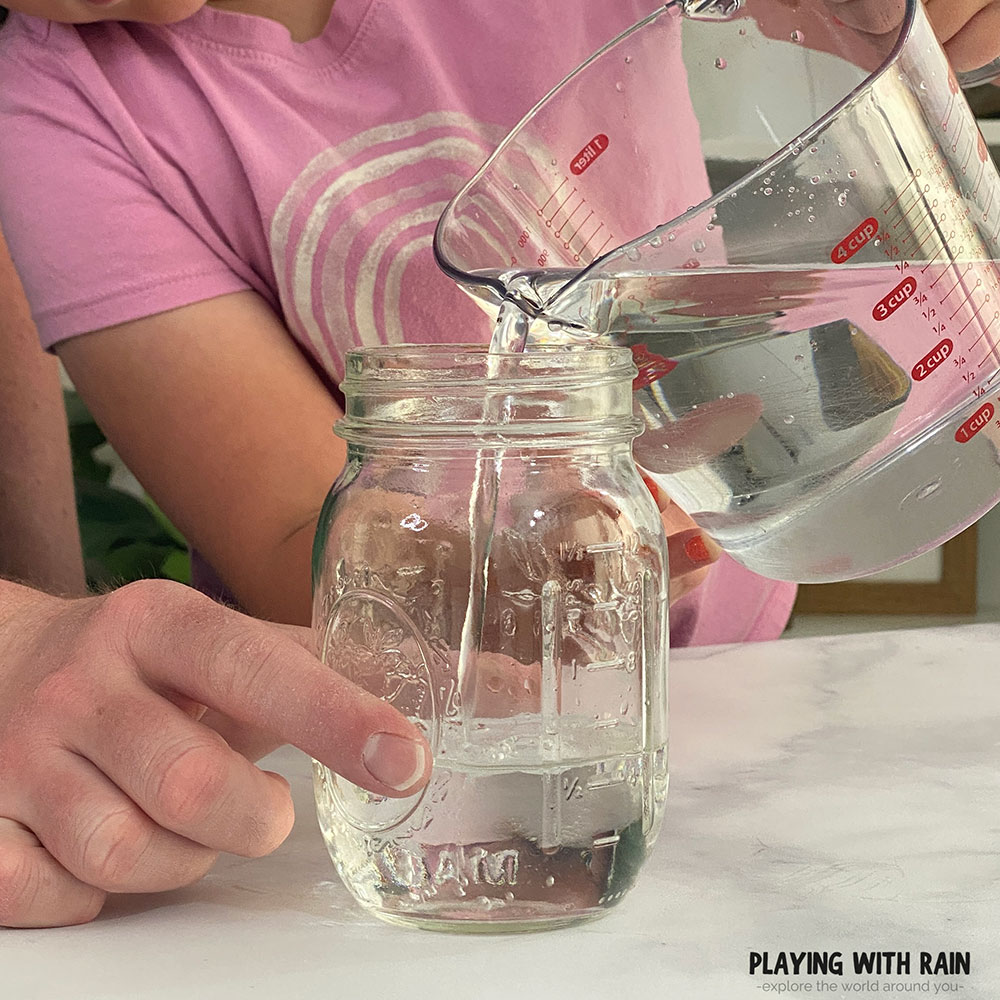 Pouring water into a glass jar