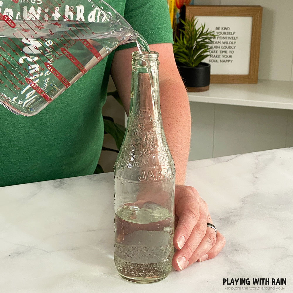 Pouring water into a narrow neck glass bottle